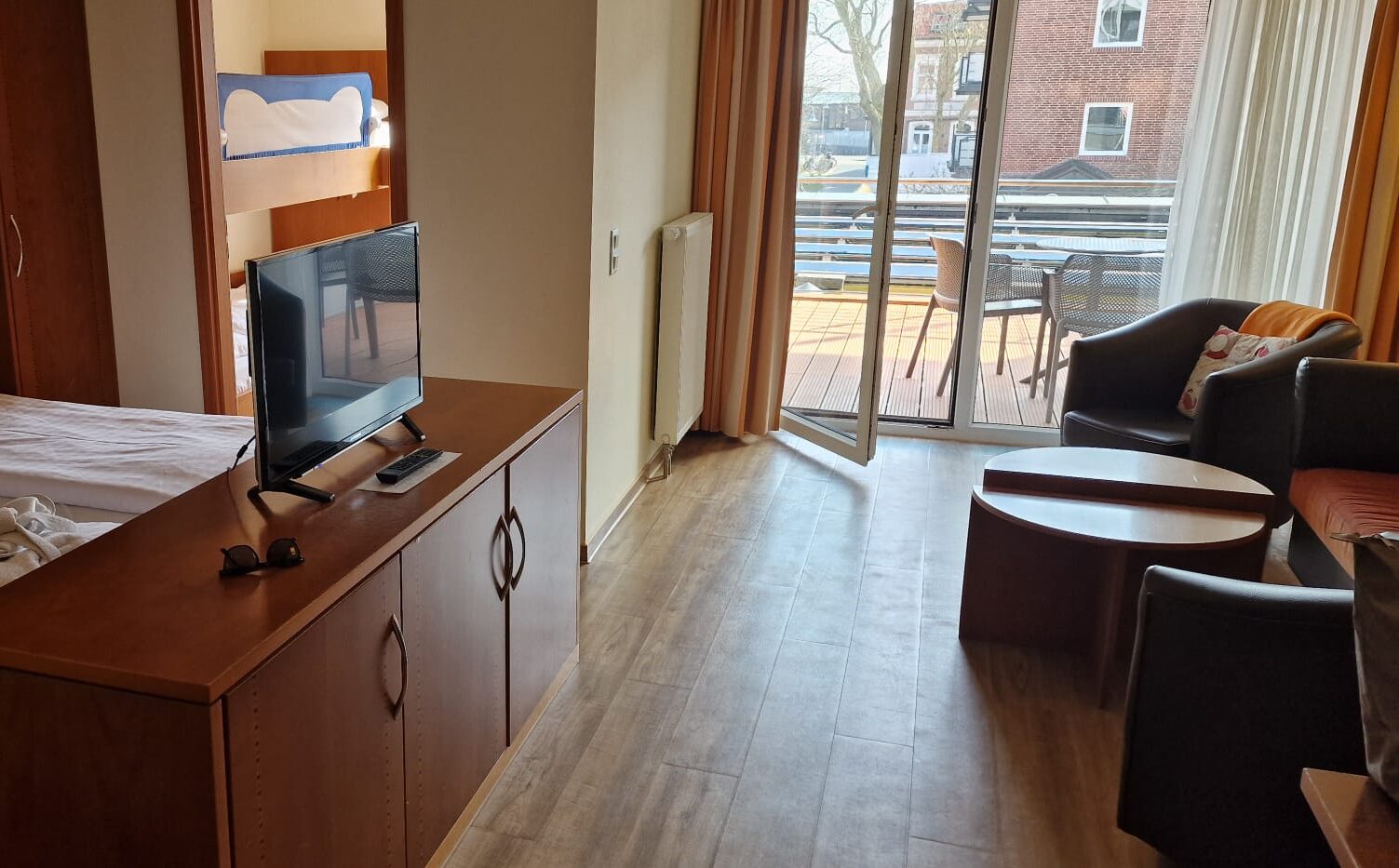 Hotelzimmer mit Sitzecke, Kommode, Doppelbett, offene Terrassentür