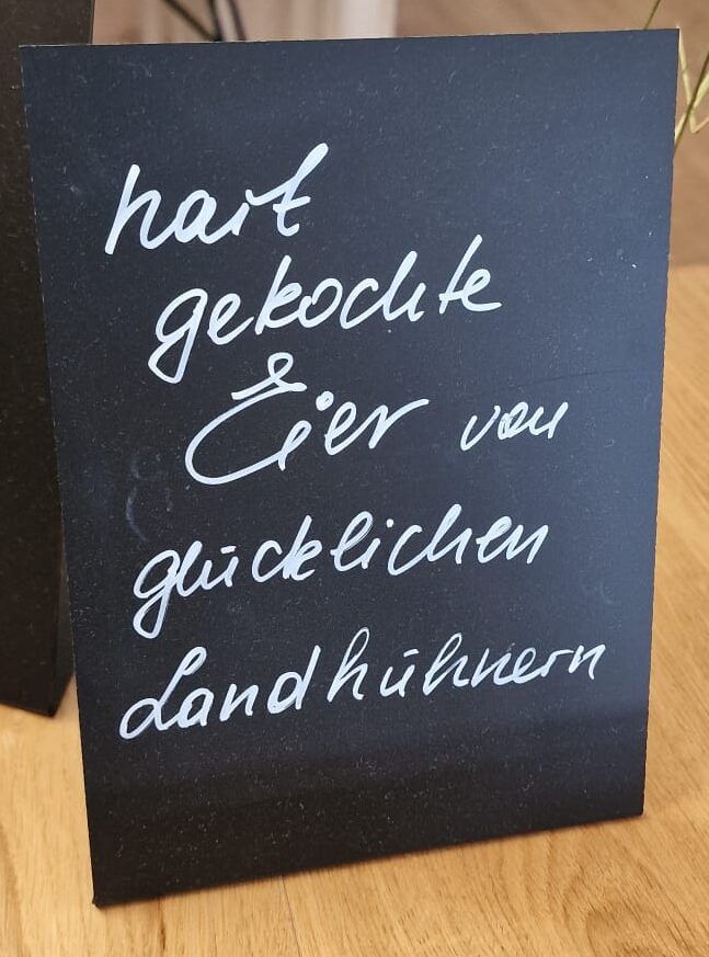 Tafel mit Kreideaufschrift "hart gekochte Eier von glücklichen Landhühnern"