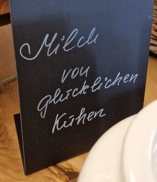 Tafelschild auf dem Frühsücksbuffet "Milch von glücklichen Kühen"